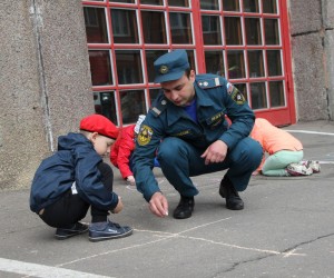 Пожарный и ребенок рисуют на асфальте 